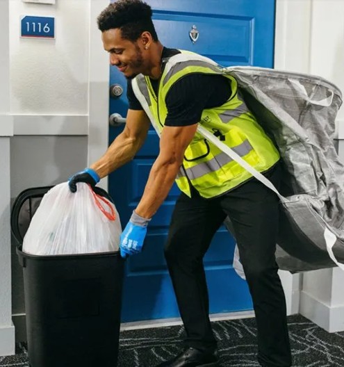 Employee picking up trash out of a trash container