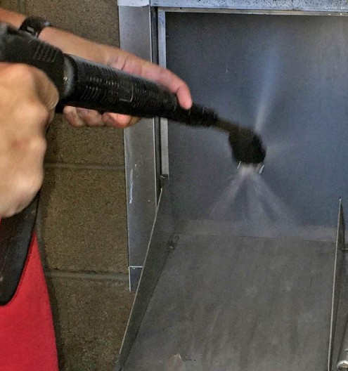 Man pressure washing a chute in an apartment complex.